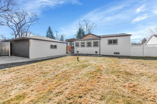 rear view of house featuring fence, an outdoor structure, and a lawn