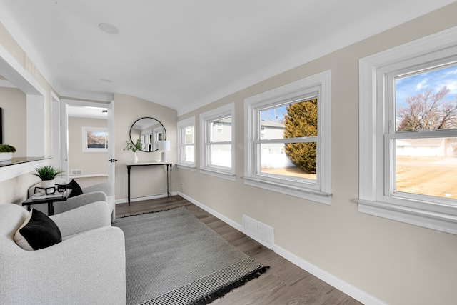 living area featuring dark wood-style flooring, visible vents, and baseboards