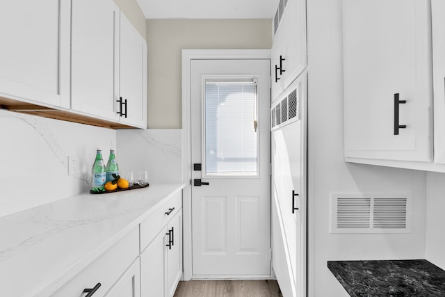 kitchen featuring stone counters, white cabinetry, and visible vents