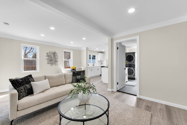 living room with stacked washing maching and dryer, light wood-style flooring, baseboards, and recessed lighting