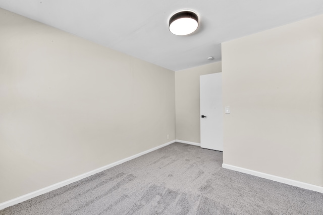 carpeted spare room featuring baseboards