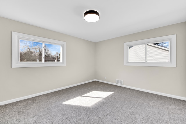 carpeted empty room featuring visible vents and baseboards