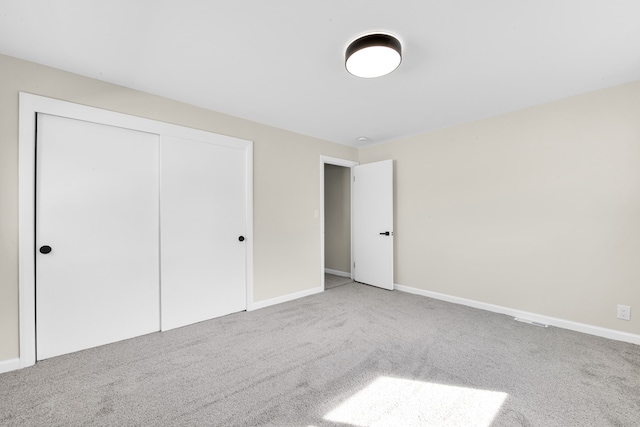 unfurnished bedroom with carpet, a closet, and baseboards