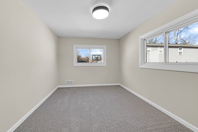 spare room featuring carpet floors, visible vents, and baseboards