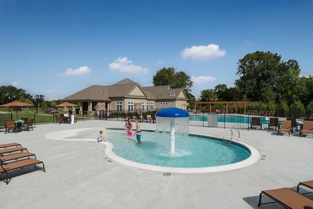 community pool with a patio area and fence