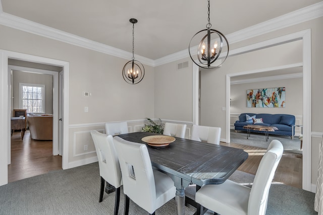 dining area featuring ornamental molding, visible vents, an inviting chandelier, and wood finished floors