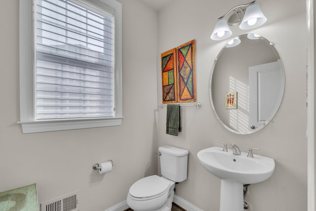 half bathroom featuring toilet, visible vents, and baseboards