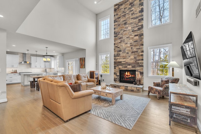 living room featuring visible vents, a healthy amount of sunlight, a stone fireplace, and light wood finished floors