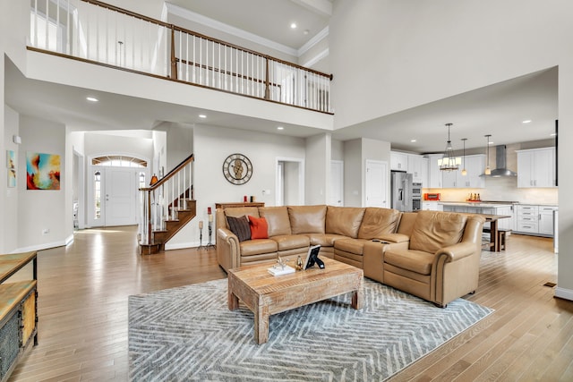 living room with a chandelier, light wood-type flooring, baseboards, and stairs