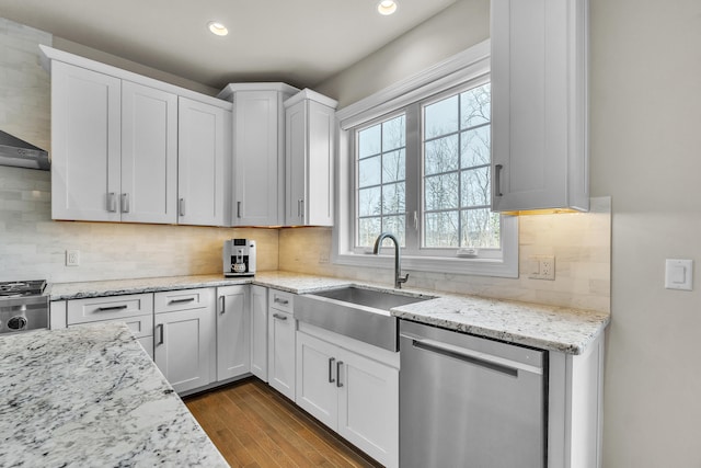 kitchen featuring tasteful backsplash, dark wood-style flooring, stainless steel dishwasher, white cabinetry, and a sink