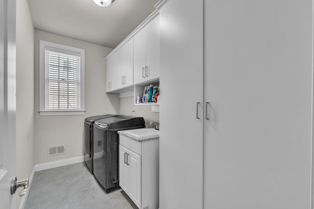 laundry room with a sink, visible vents, baseboards, cabinet space, and washer and clothes dryer