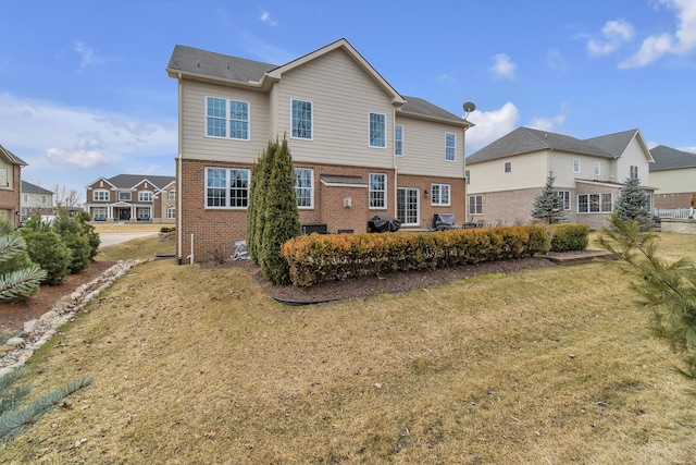 back of property featuring a lawn and brick siding