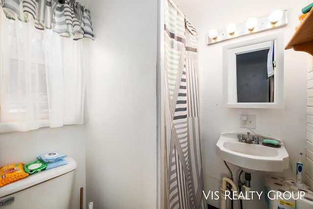 bathroom with a shower with shower curtain, a sink, and toilet