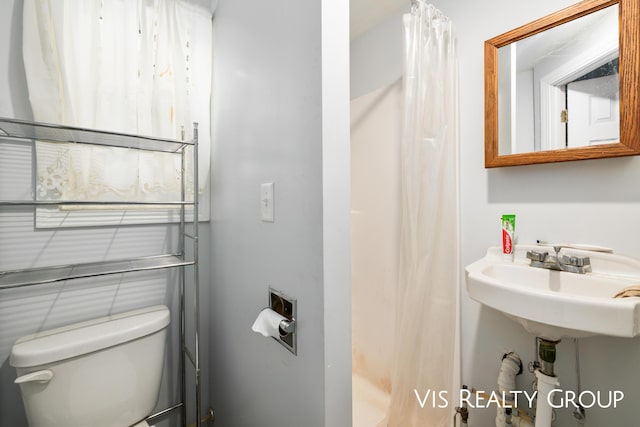 full bath with toilet, a sink, and a shower with shower curtain