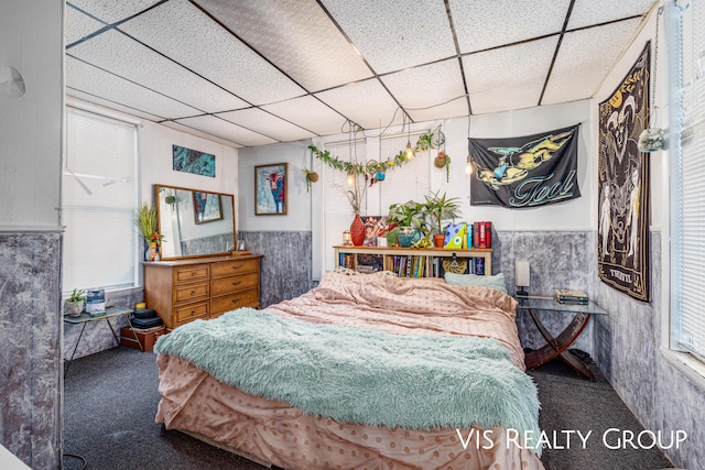 bedroom with carpet floors, a drop ceiling, and wainscoting