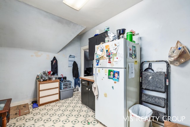 kitchen featuring vaulted ceiling, light countertops, and freestanding refrigerator