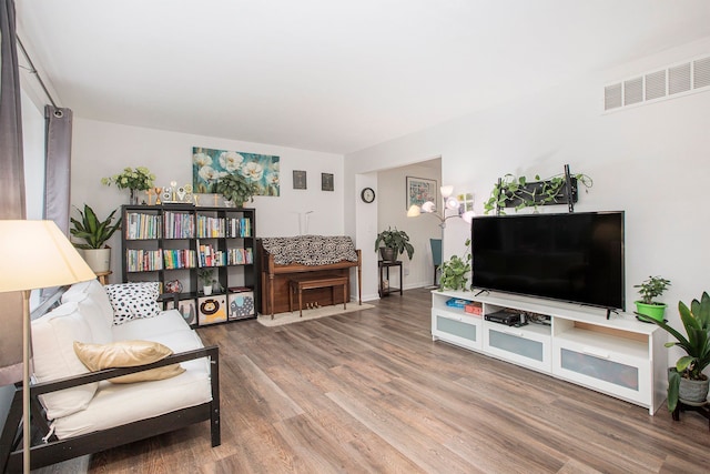 living room with baseboards, visible vents, and wood finished floors