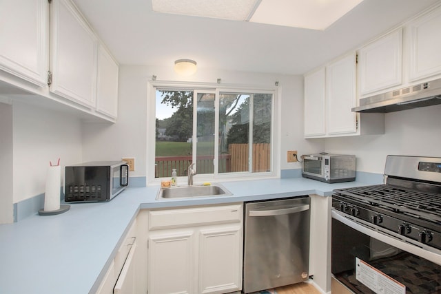 kitchen with stainless steel appliances, light countertops, white cabinetry, a sink, and under cabinet range hood