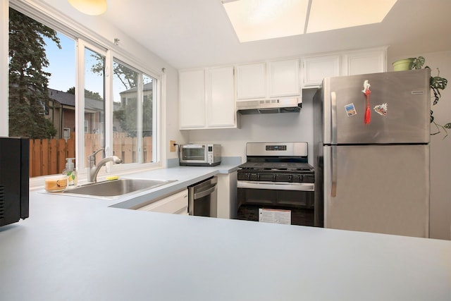 kitchen with under cabinet range hood, stainless steel appliances, a sink, white cabinets, and light countertops