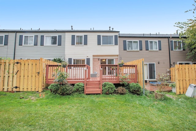 rear view of property featuring fence, a deck, and a yard