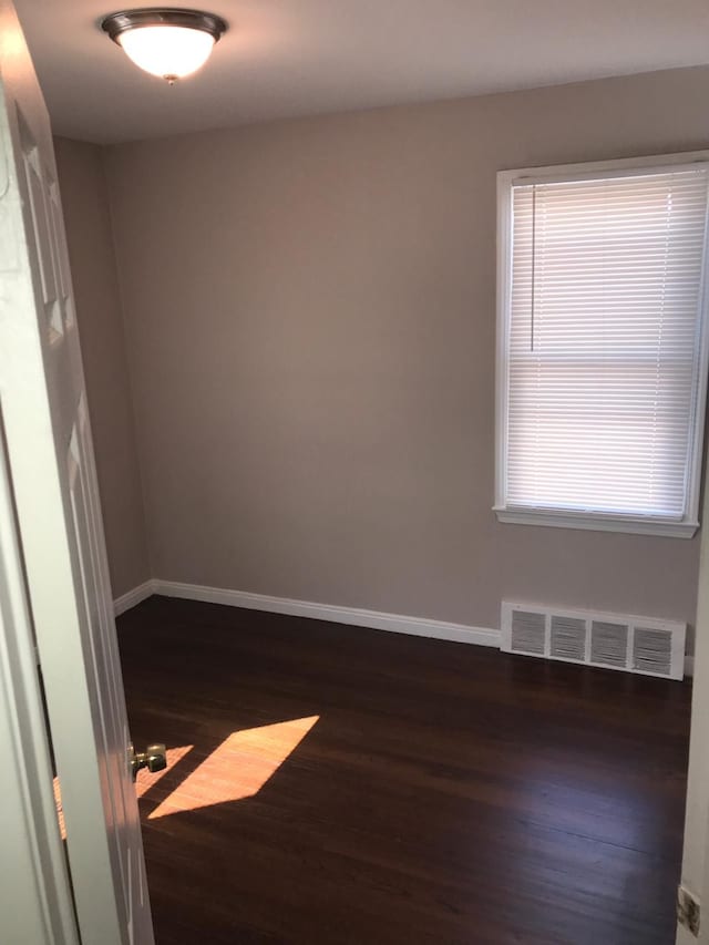 empty room featuring baseboards, visible vents, and wood finished floors