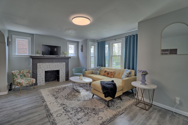 living area featuring baseboards, wood finished floors, and a tiled fireplace