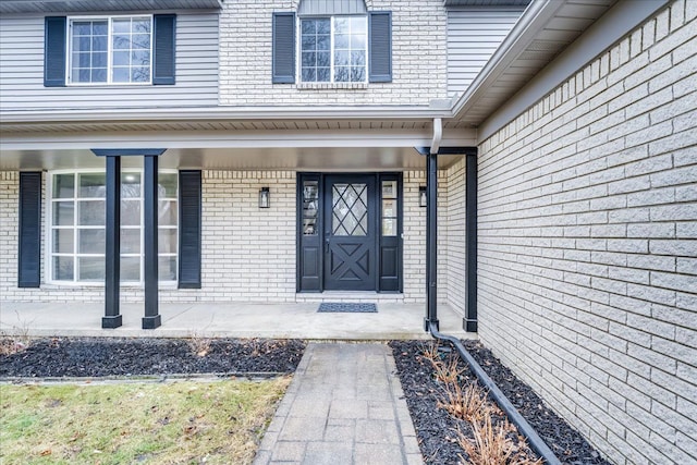 entrance to property with covered porch and brick siding