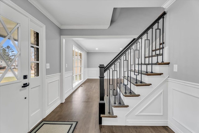 entryway featuring dark wood-style floors, ornamental molding, and a decorative wall