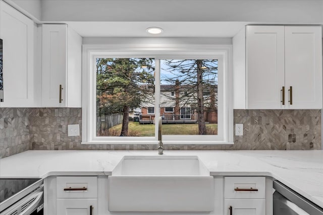 kitchen with stainless steel dishwasher, tasteful backsplash, white cabinetry, and a sink