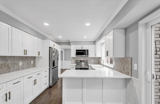 kitchen with ornamental molding, dark wood-type flooring, stainless steel appliances, light countertops, and a sink