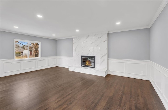 unfurnished living room with a premium fireplace, ornamental molding, wood finished floors, and recessed lighting