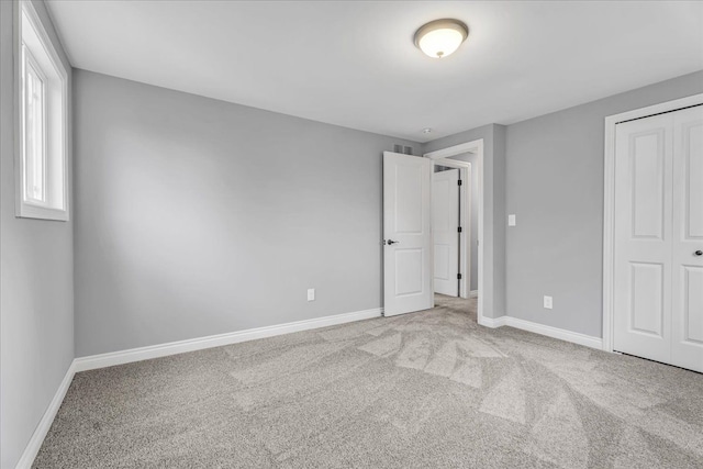 unfurnished bedroom with a closet, baseboards, and carpet flooring