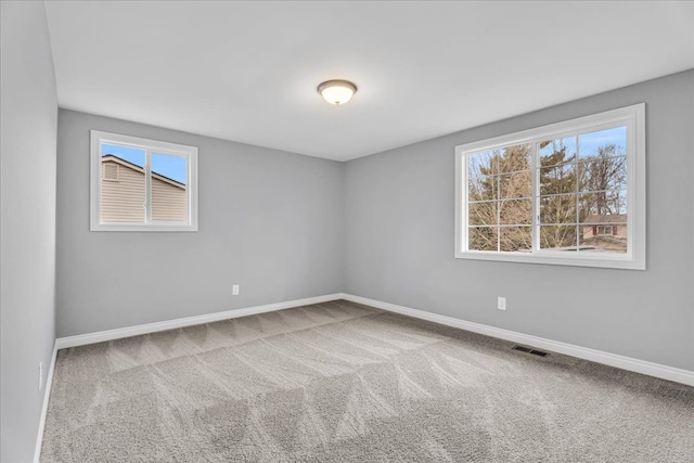 unfurnished room featuring carpet flooring, visible vents, and baseboards