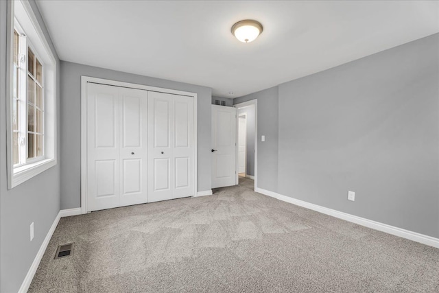 unfurnished bedroom with baseboards, a closet, visible vents, and carpet flooring