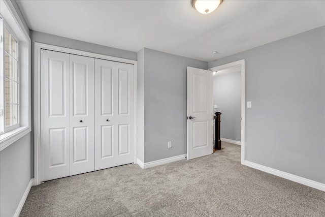 unfurnished bedroom featuring a closet, baseboards, and carpet flooring