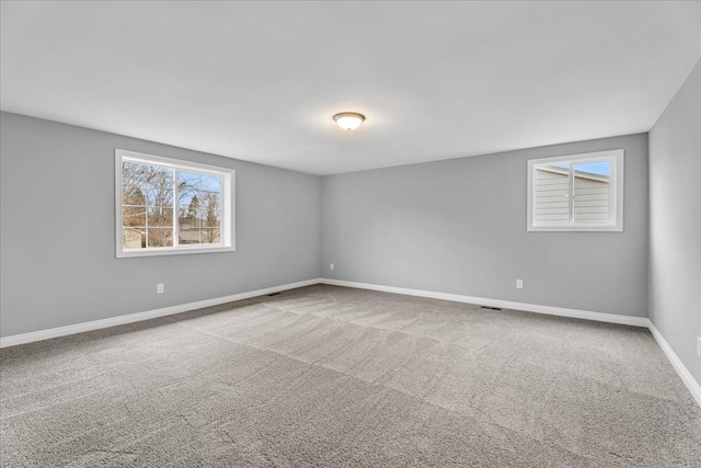 carpeted empty room featuring a wealth of natural light and baseboards