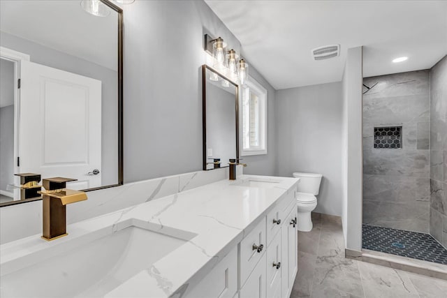 bathroom featuring toilet, tiled shower, a sink, and visible vents