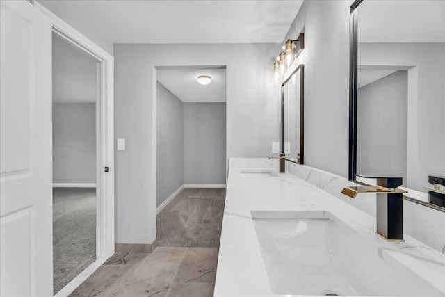 bathroom featuring a sink, baseboards, and double vanity