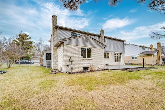 back of property with a yard, brick siding, a chimney, and a patio