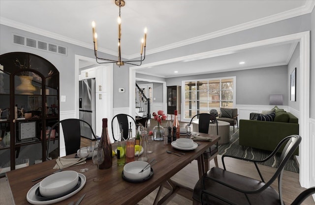 dining room with crown molding, visible vents, stairway, wainscoting, and a chandelier