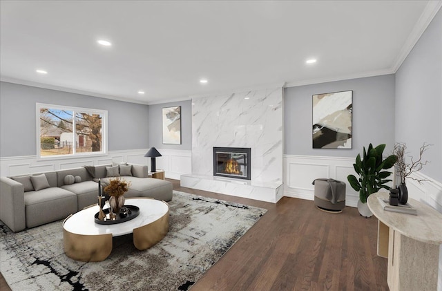 living room featuring a fireplace, dark wood-style flooring, crown molding, and recessed lighting