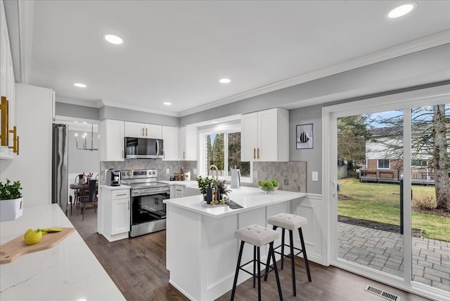 kitchen with stainless steel appliances, white cabinets, visible vents, and crown molding