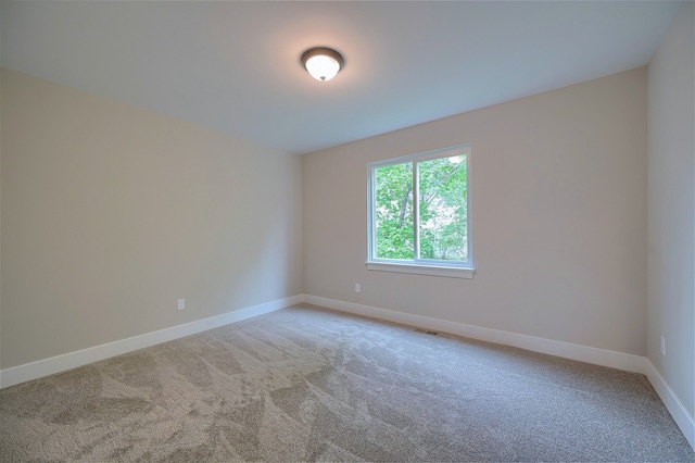 empty room featuring carpet floors, visible vents, and baseboards