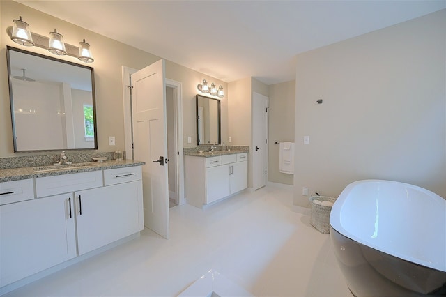 bathroom with a soaking tub, two vanities, and a sink