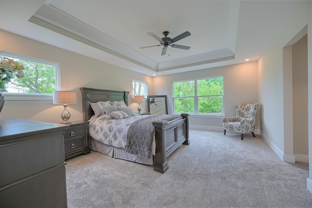 bedroom with ceiling fan, baseboards, a raised ceiling, and light colored carpet