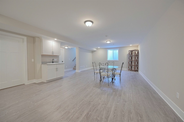 dining space featuring baseboards, stairway, and light wood finished floors