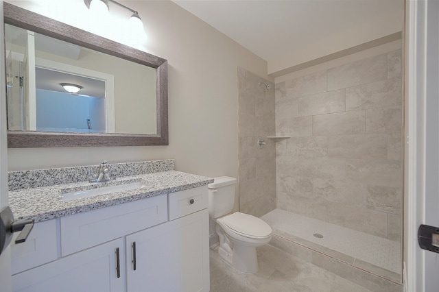 full bath featuring tiled shower, vanity, and toilet