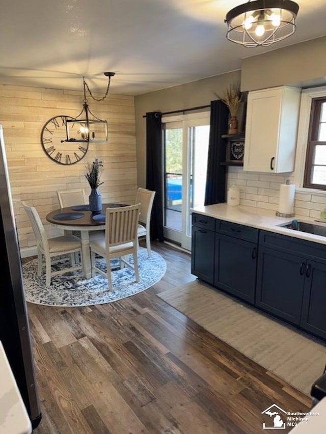 dining area featuring wood walls, wood finished floors, and a notable chandelier