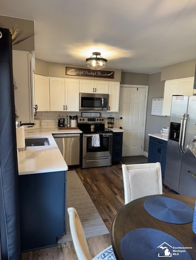 kitchen featuring white cabinets, dark wood-style flooring, stainless steel appliances, and light countertops