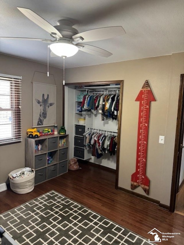 bedroom with a closet, wood finished floors, a ceiling fan, and baseboards